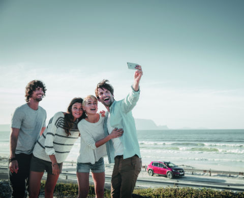 חברה בסלפי על רקע רכב פיג'ו אדום